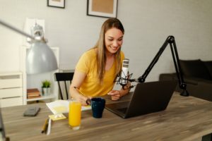 Woman podcaster making a podcast from. Female working from home recording a podcast on a laptop.