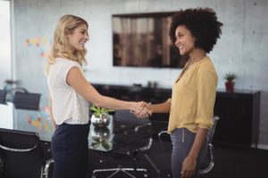 Businesswomen shaking hands in meeting room at creative office